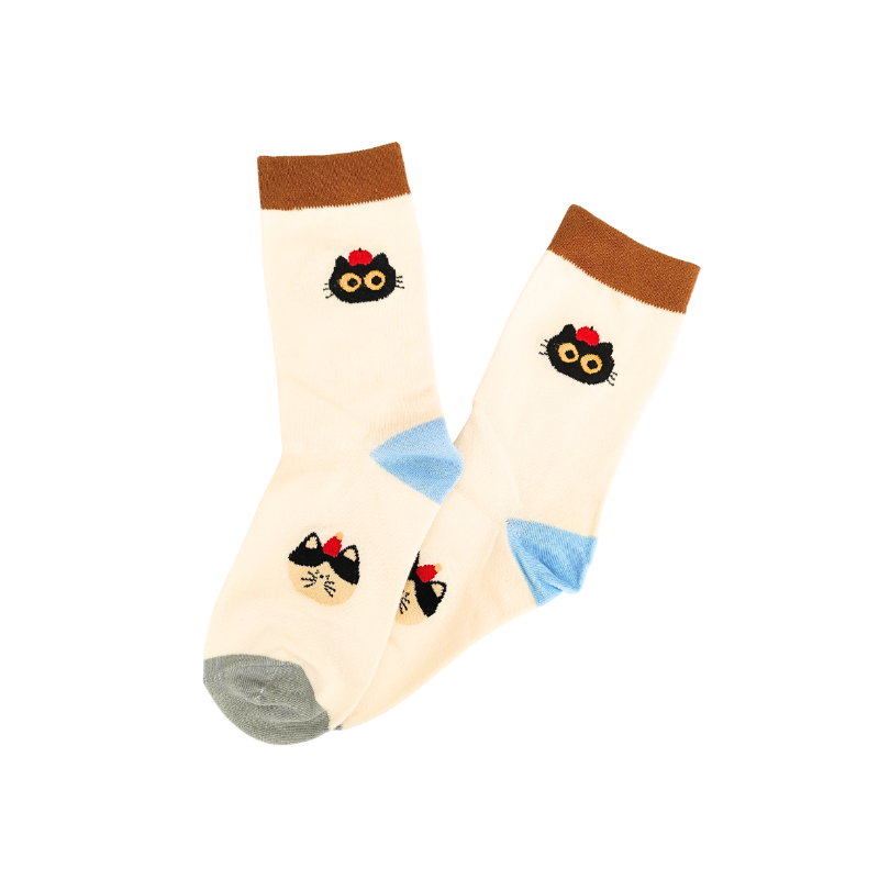 Cream crew socks with brown cuffs, blue heels, grey toes, and two black cat‑face designs with yellow eyes and red bows.