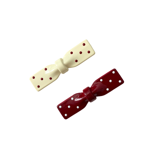 Two polka dot bows, one cream and one red, on a white background.