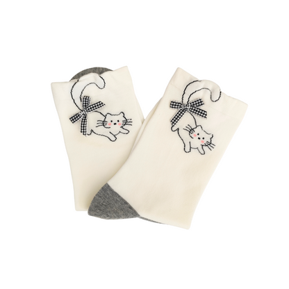 White crew socks with grey toes and an embroidered cat wearing a checkered bow near the cuff.