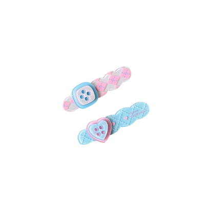 A sweet pastel hair clip duo featuring a pink criss‑cross clip with a button detail and a blue quilted clip with a heart button — perfect for soft‑girl, kawaii, and everyday cute hairstyles.