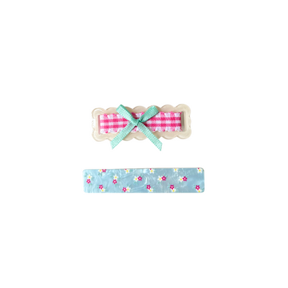 A sweet 2‑piece pastel hair clip set featuring a scalloped gingham bow clip and a floral blue clip — perfect for soft‑girl, kawaii, and everyday cute hairstyles.
