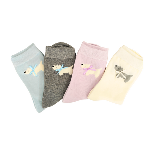 Four pairs of knit crew socks in light blue, dark grey, light pink, and cream, each featuring a small embroidered dog with a bow near the cuff
