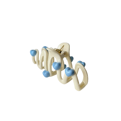 Cute wavy hair clip with blue heart details in a cream colour, sweet and playful hair accessory for girls on a white background