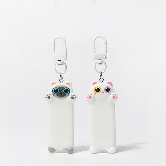 Two white cat-shaped keychains with colorful eyes on a light gray background, 
