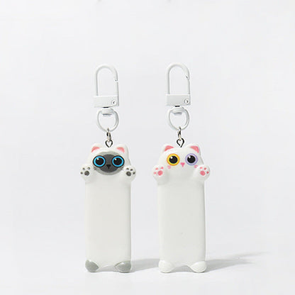 Two white cat-shaped keychains with colorful eyes on a light gray background, 
