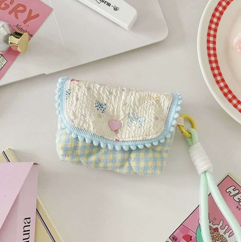 A cheerful gingham body with a whimsical flap decorated with tiny bows and stars. Light‑blue pom‑pom trim and a mint‑green strap with a yellow clip complete the fun, youthful design.
