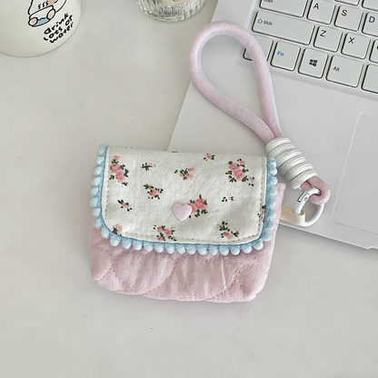 Small floral pouch with a pink strap on a light surface