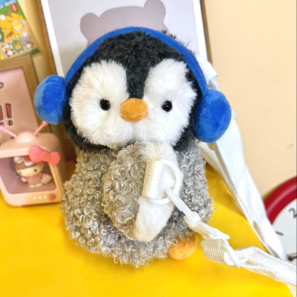 Fluffy grey penguin mini backpack with blue earmuffs worn over the shoulder with white straps