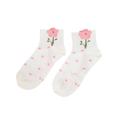 White ankle socks with pink polka dots and a pink flower with a green stem near the cuff