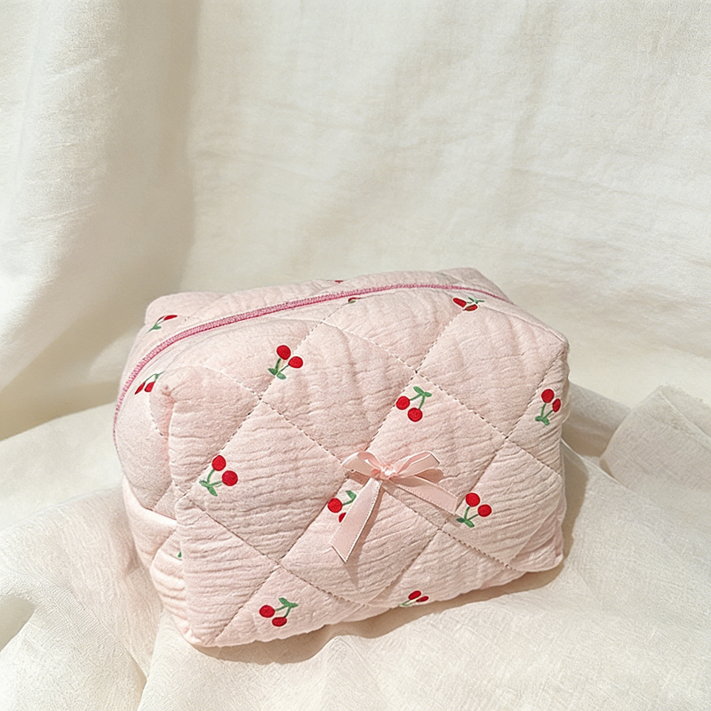 Pink quilted pouch with cherry pattern on a soft white background