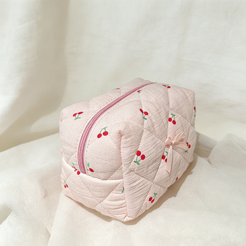 Pink quilted pouch with cherry designs on a white background