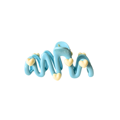 Cute wavy hair clip with cream heart details in a pastel blue colour, sweet and playful hair accessory for girls on a white background