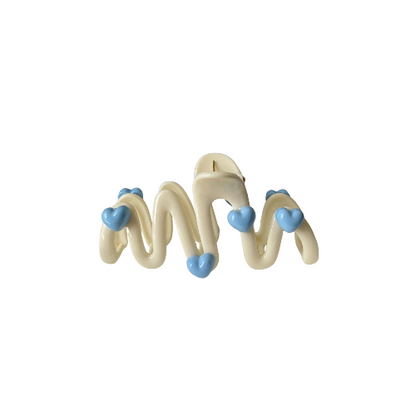 Cute wavy hair clip with blue heart details in a cream colour, sweet and playful hair accessory for girls on a white background